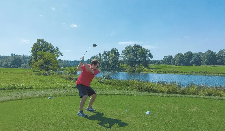 A golfer playing golf and  hitting the ball  