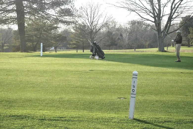 A golf bag set and a golfer in the ground on the putting green