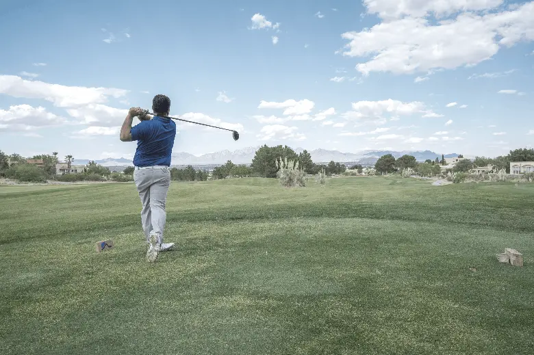 A golfer hits the ball and swings the driver