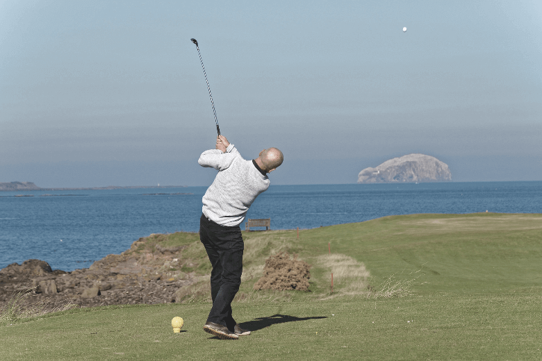 A golfer swings the ball to the hole